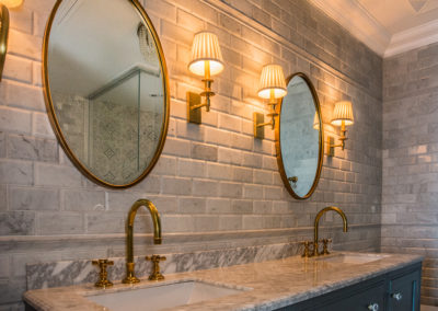 bathroom - mirror - brass - gold - tall faucett - classic - marble countertop - lamp - lights - brick - backsplash - crown molding - modern -