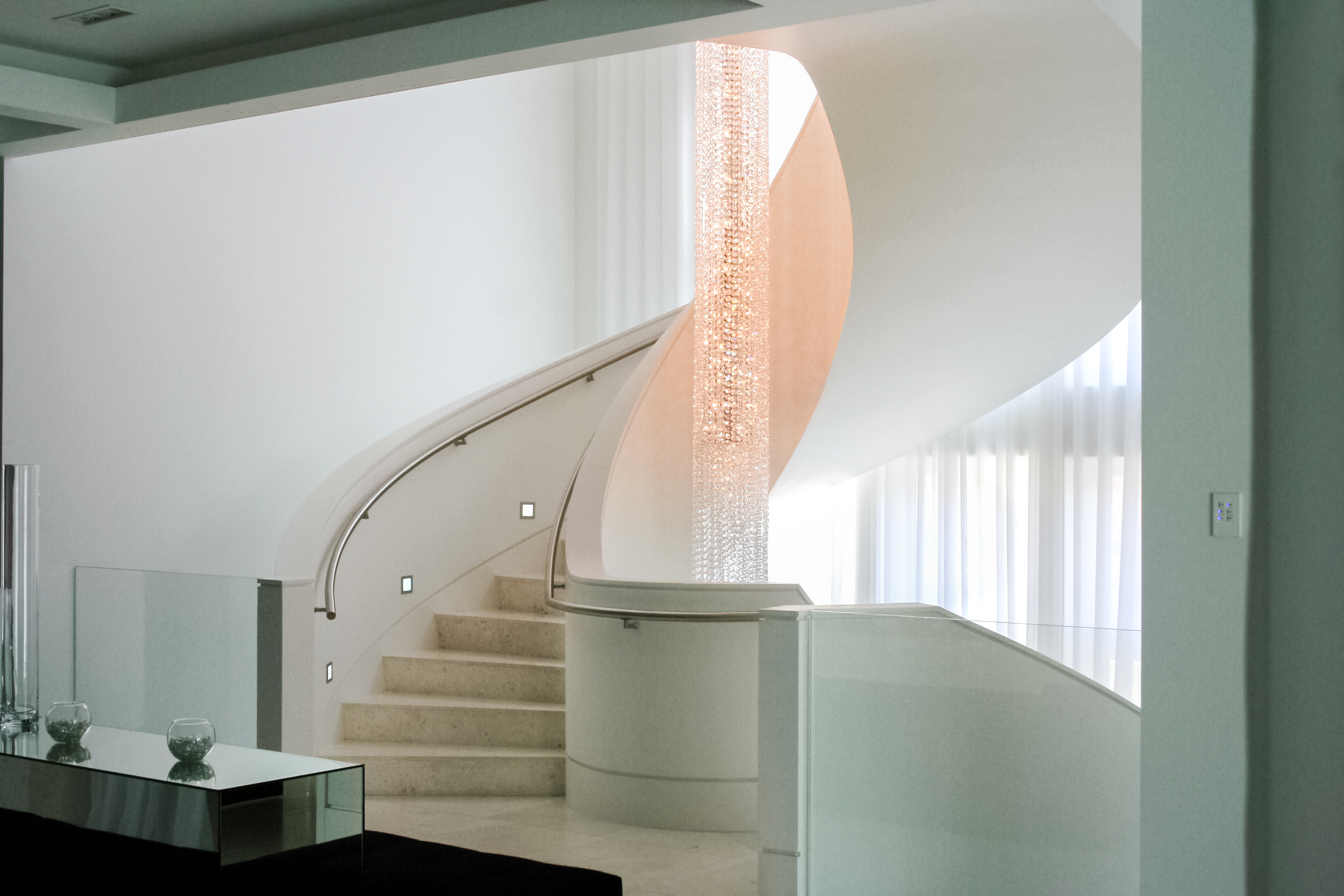 marble - chandelier - stairs - chrome railing - lights - winding - exquisite details - contemporary - white walls - sheer curtains